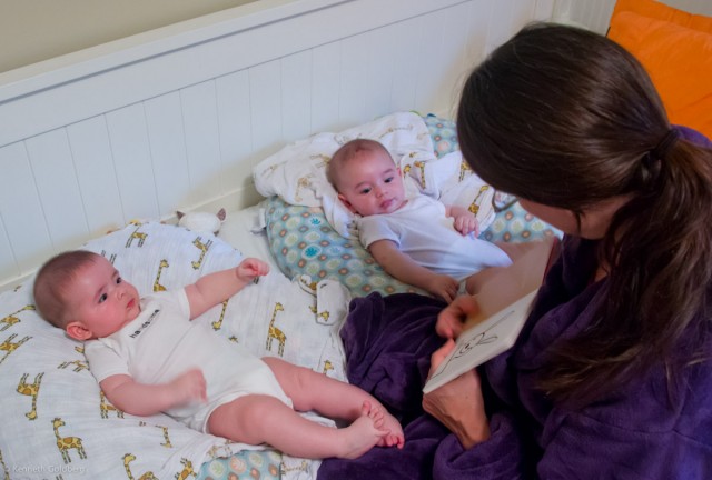 twin brothers, baby boys, max and sam sit on Boppy Newborn Loungers wearing white onesies while their mother reads the book, Not A Box, to them