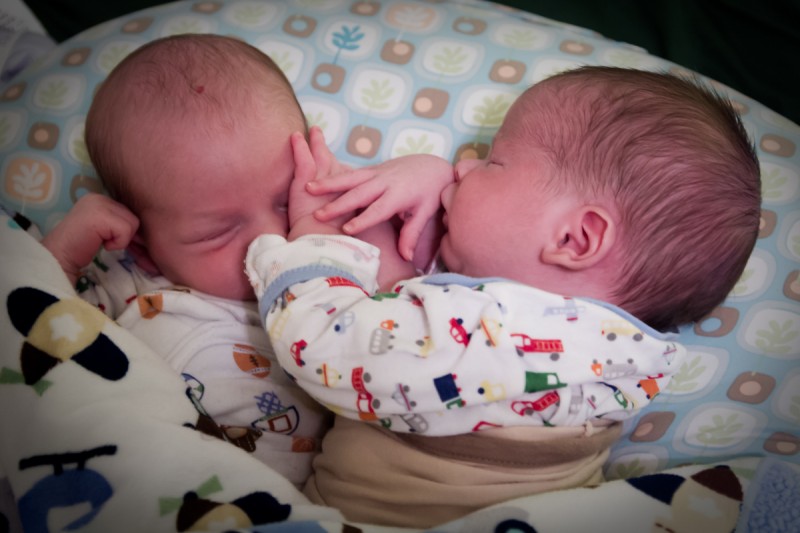 twin baby boys max and sam sit on a Boppy pillow with their hands in each others faces