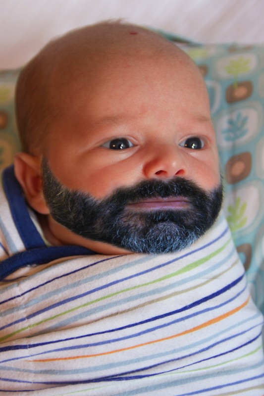 baby boy Sam, swaddled and sitting on a boppy, photoshopped with his father's beard