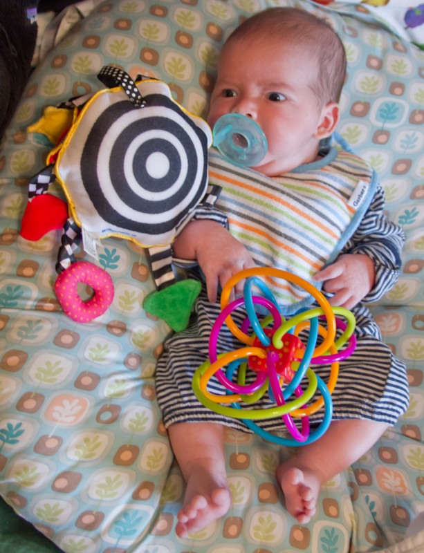 baby boy Max on a Boppy with complex toys, like a Whoozit