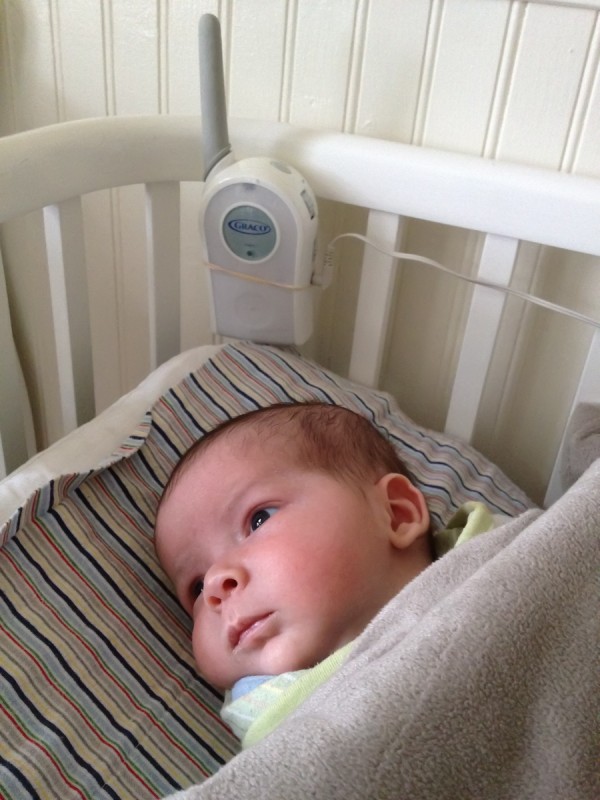 baby boy max lies awake in a BAM bassinet, below a Graco baby monitor