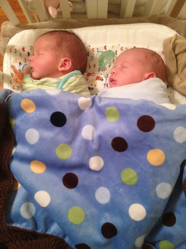 baby boys Max and Sam in a BAM Bassinet, sleeping under the same blanket, facing the same way