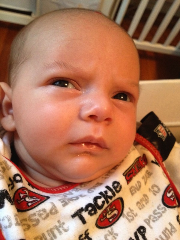 baby sam, wearing a 49ers bib, looks off to the side contemplatively