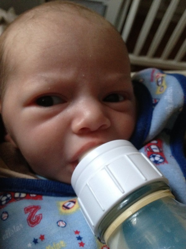 baby boy Sam drinking from a bottle, looking a bit perturbed