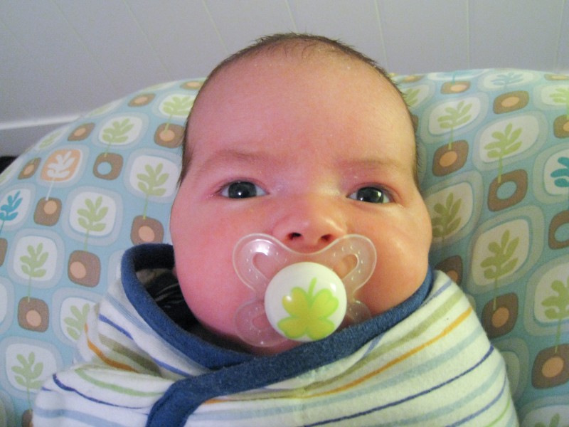 baby boy max, close-up with a pacifier, sits on a Boppy