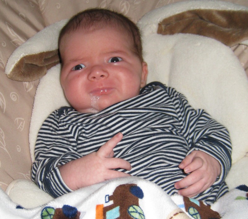 baby boy max, wearing a striped shirt, spits up while sitting in a My Little Snugabunny Baby Bouncer