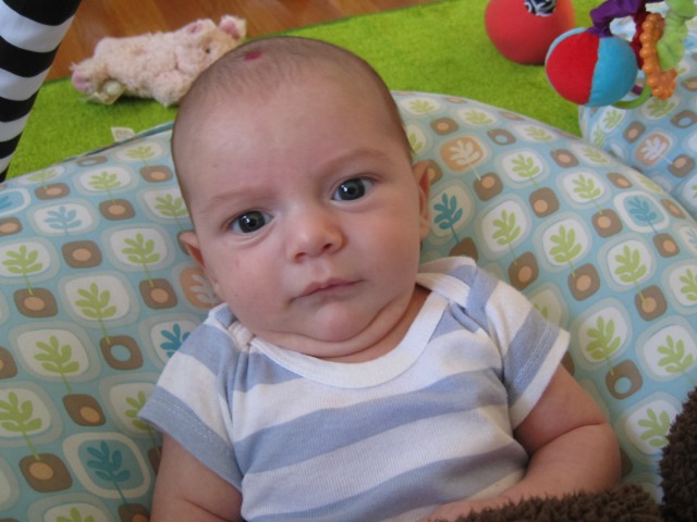 baby boy sam sits on a Boppy Newborn Lounger and looks at the camera with a funny expressin
