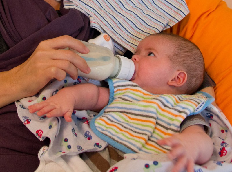 baby boy max wearing a striped bib drinks milk from a bottle