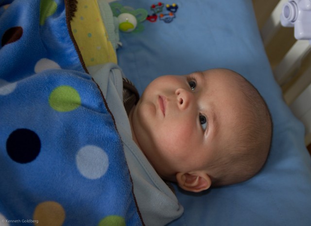 baby boy max lies awake in his crib, staring upward thoughtfully
