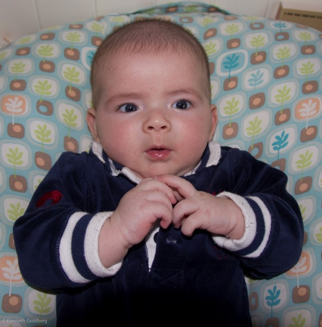Baby boy max, wearing a black Polo outfit, sits on a BoppyNewbornLounger, while giving insight to his father