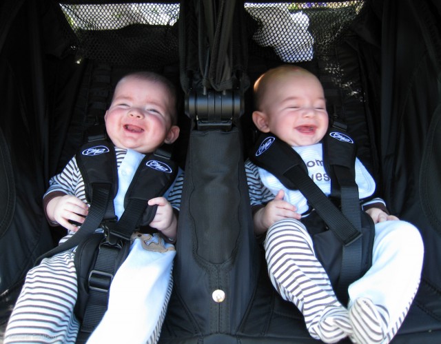 twin brothers max and sam laugh while strapped into a city mini GT double stroller