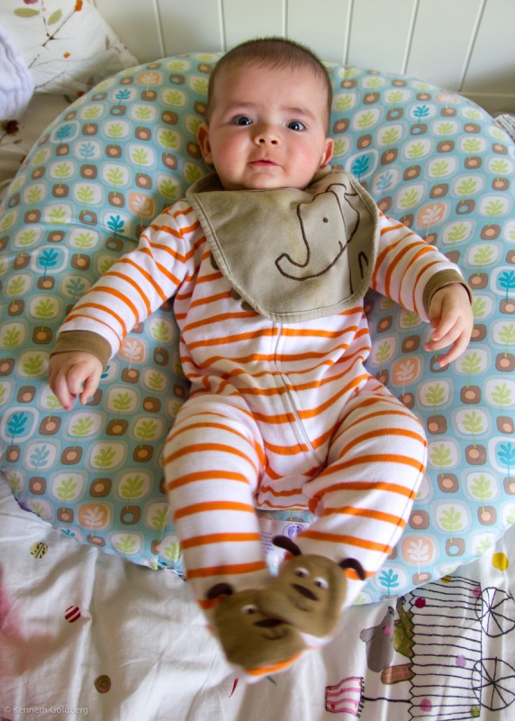 baby boy max sits on a Boppy Newborn Lounger wearing an orange striped suit and an elephant bib