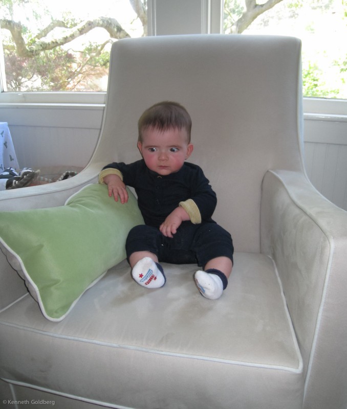 baby boy max sits in a big chair, looking serious