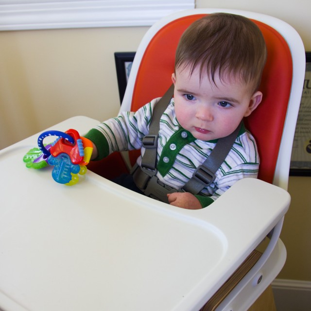 baby boy max, holding a set of colorful keys, presides over the high chair