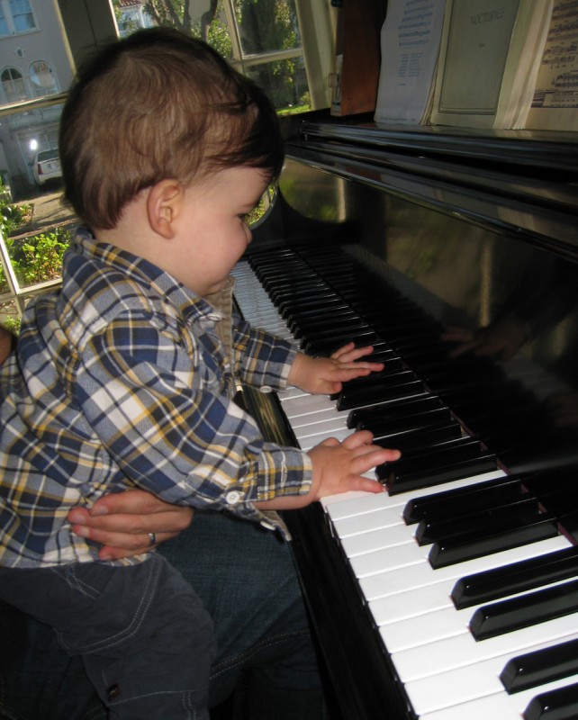 baby boy max sits at the piano and plays